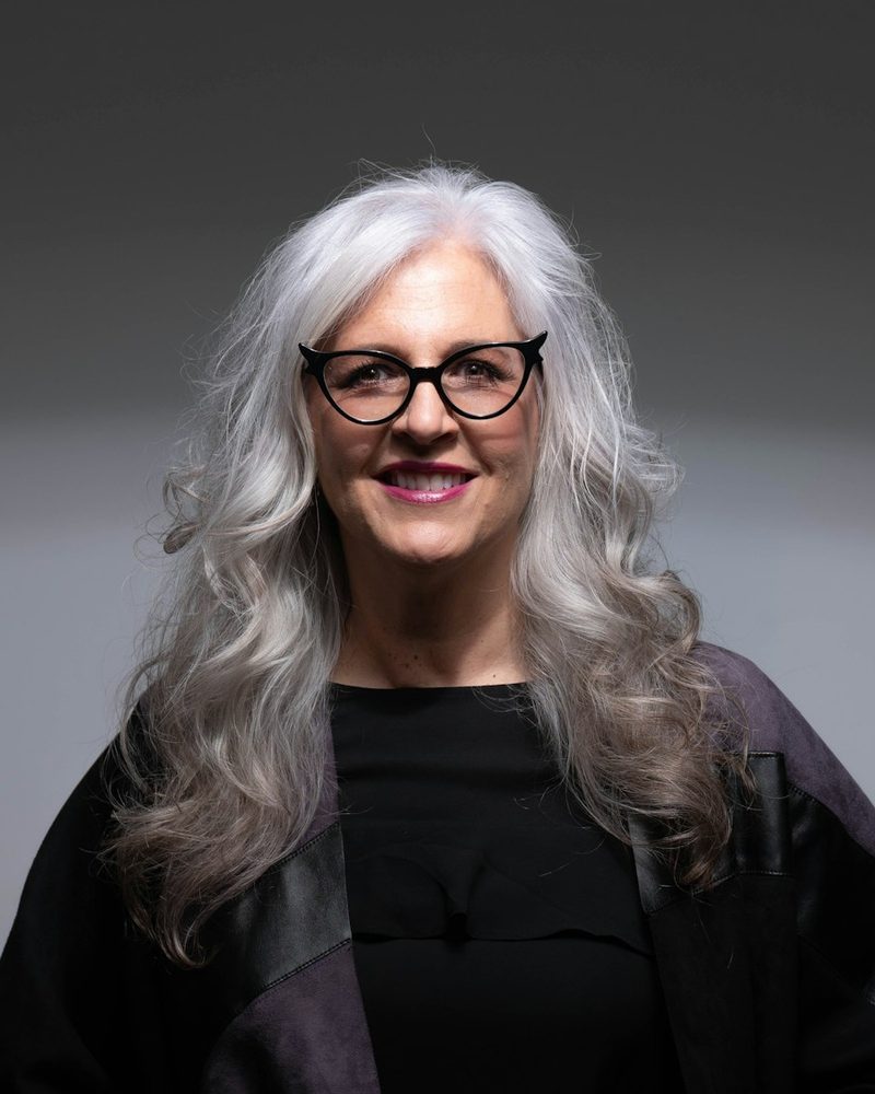 Portrait von Margarete Amann mit langen grauen Haaren, Brille und dunkler Kleidung
