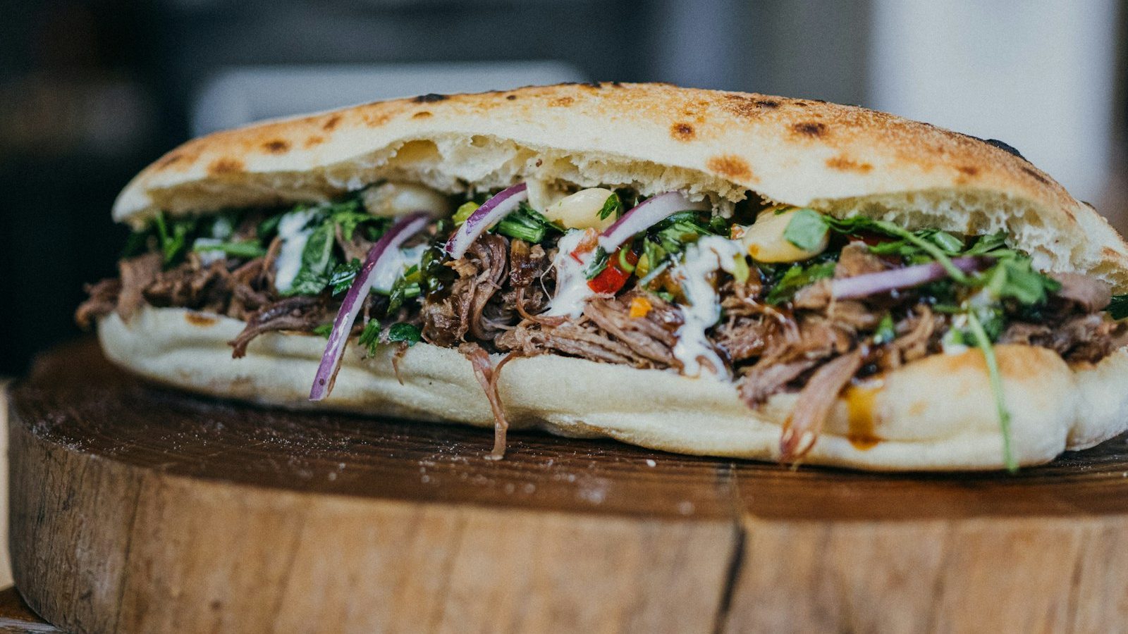 Moderne Website für einen Dönerladen, Beispielansicht: Döner im Fladenbrot mit Fleisch, roten Zwiebeln, Kräutern und Joghurtsoße auf einem Holzbrett, dahinter warmes Licht