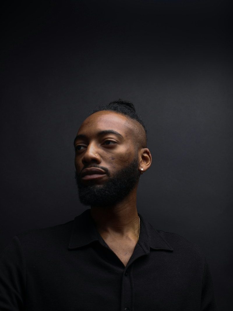 Portrait von Murat, Barber, mit Vollbart und schwarzem Hemd vor dunklem Hintergrund