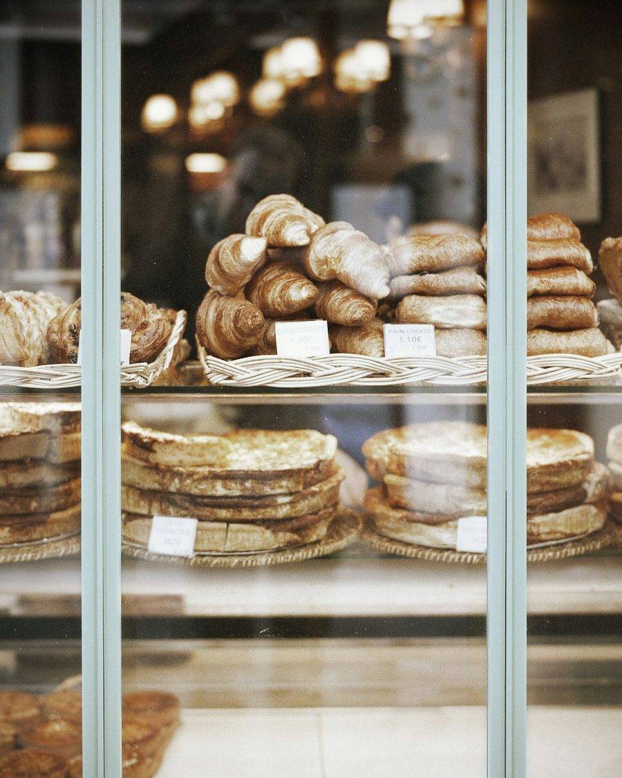 Glasvitrine mit Croissants, Plundergebäck und Apfeltaschen in Körben, dazu kleine Preisschilder