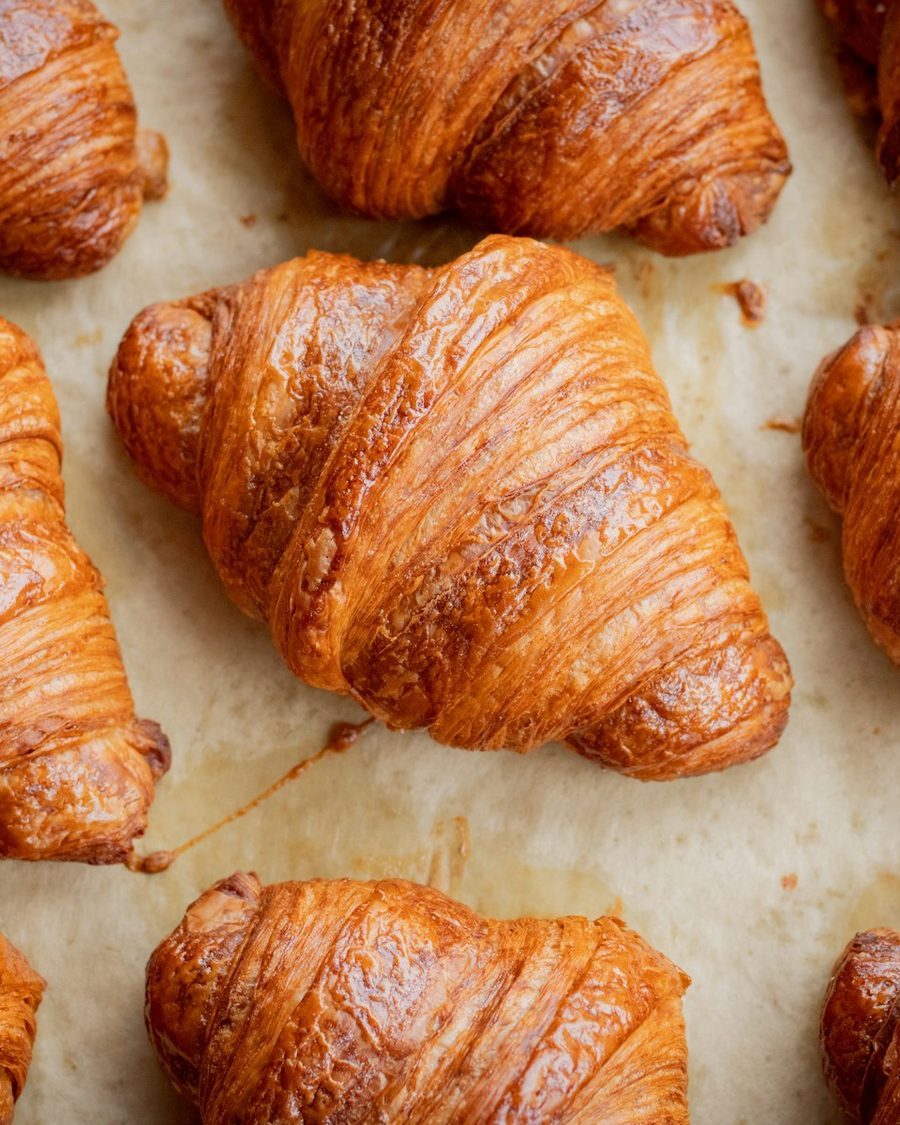 Frisch gebackene Buttercroissants auf Backpapier, von oben fotografiert