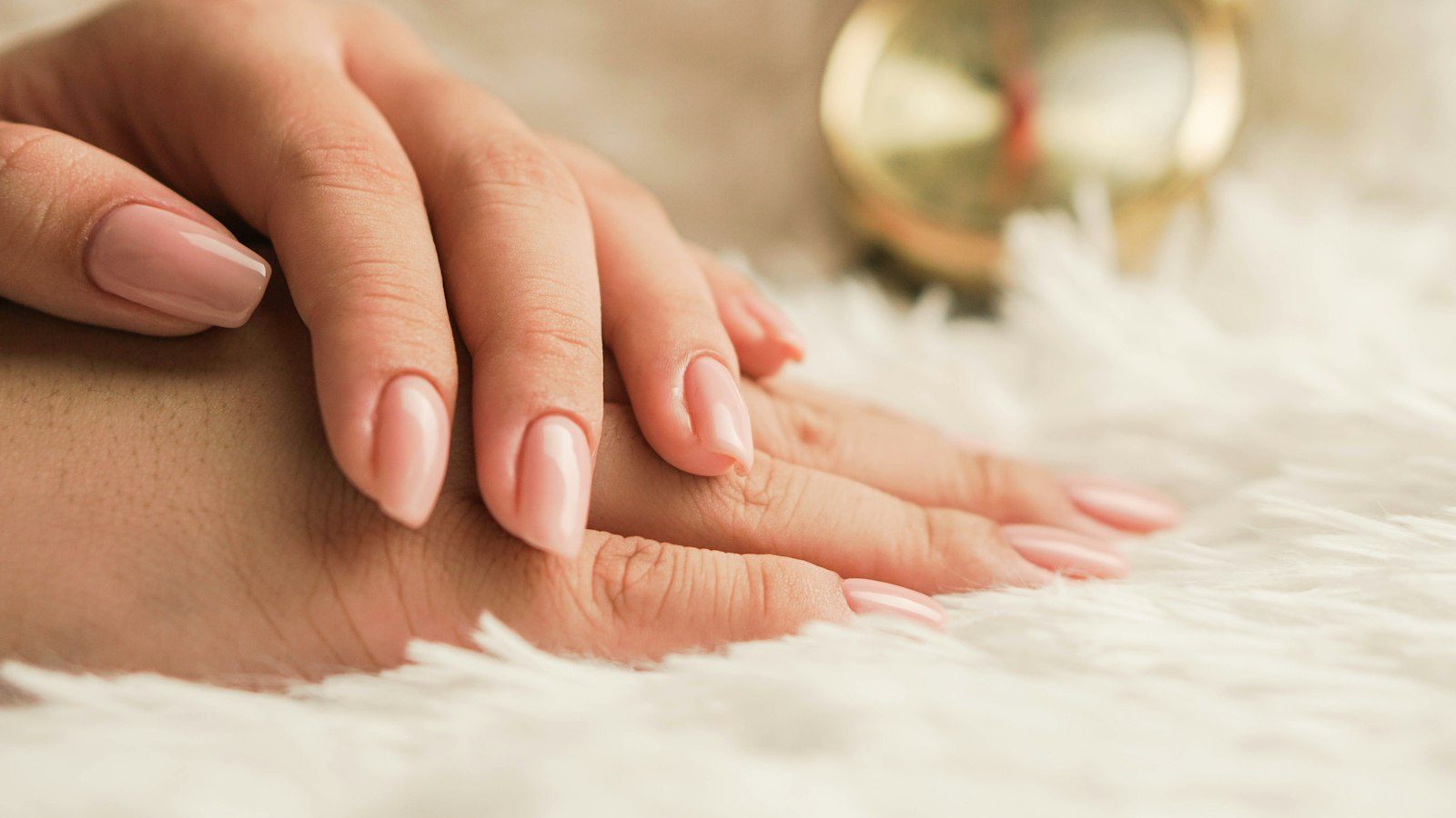 Moderne Website für ein Kosmetikstudio, Beispielansicht: zwei Hände mit gepflegten, nudefarbenen Nägeln auf hellem Fell, im Hintergrund unscharf eine goldene Uhr