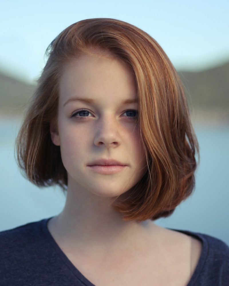 Portrait von Marie mit kinnlangen roten Haaren und Sommersprossen vor einem See