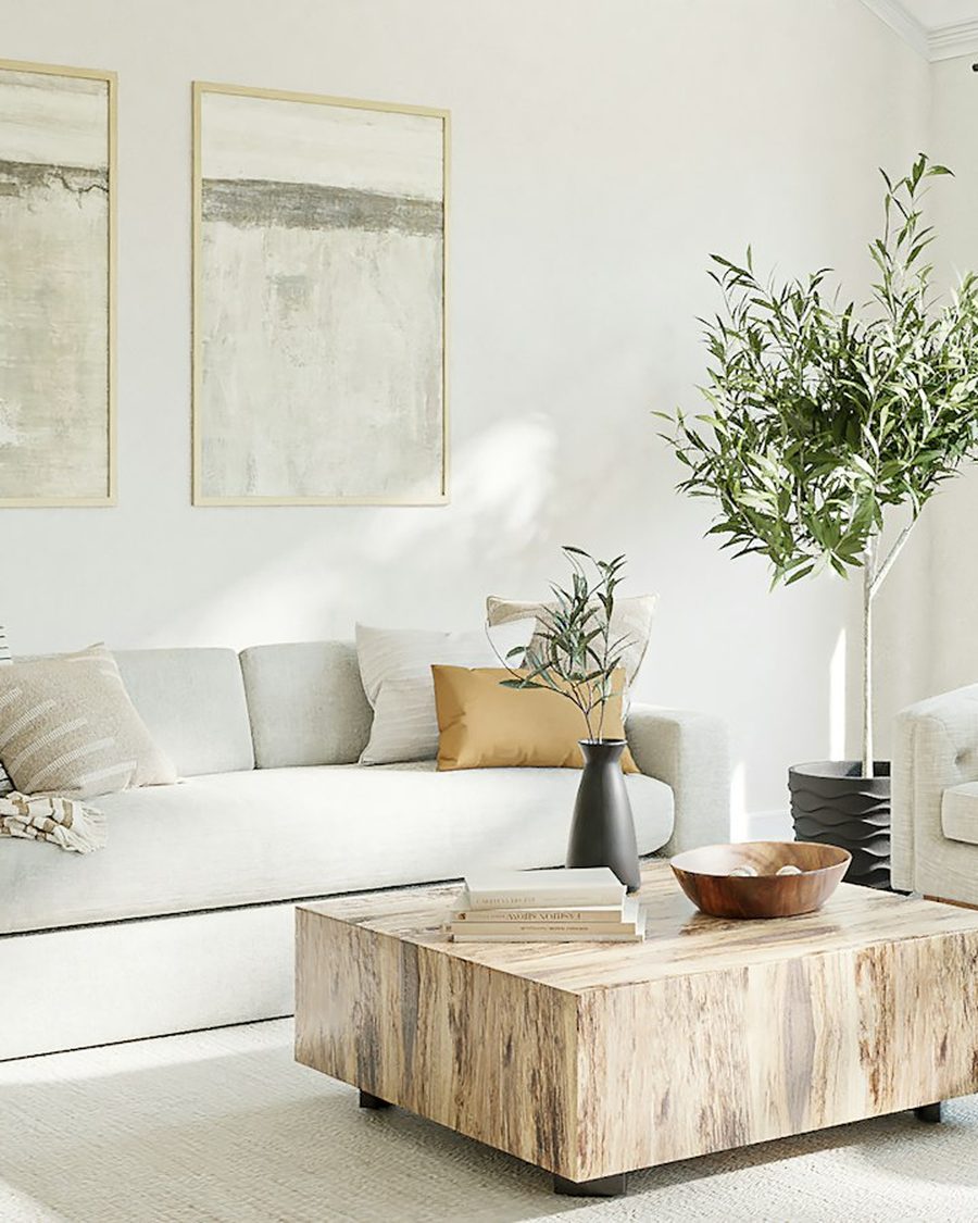 Helles Wohnzimmer mit weißen Wänden, zwei gerahmten Bildern, hellem Sofa und Holztisch