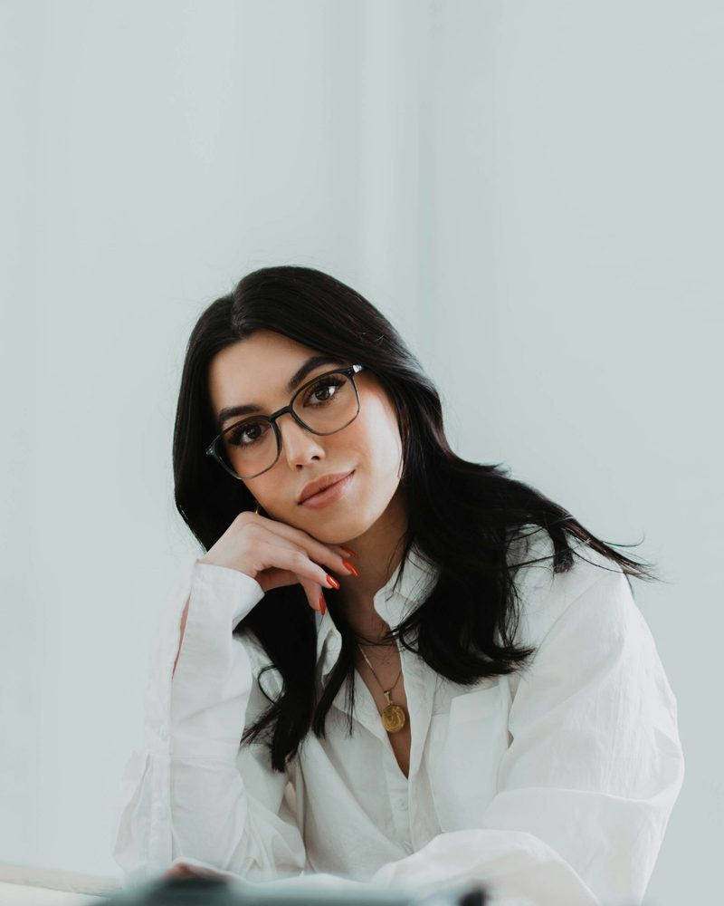 Portrait von Nina Sommer mit langen dunklen Haaren, dunkler Brille und weißer Bluse