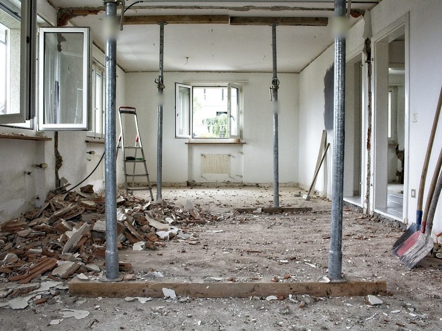 Entkernte Etagenwohnung mit Baustützen unter der Decke, Schutt am Boden und offenen Fenstern