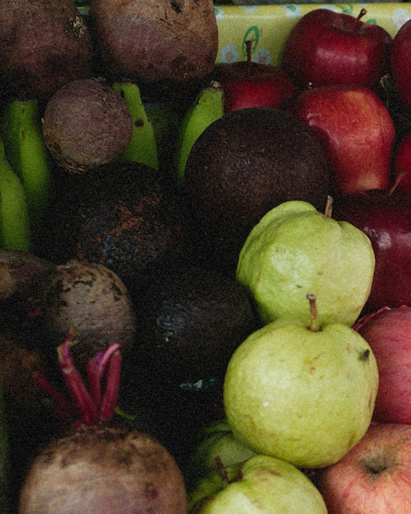 Obststand mit roten Äpfeln, hellgrünen Birnen, Roter Bete und Gurken, dicht nebeneinander aufgeschichtet