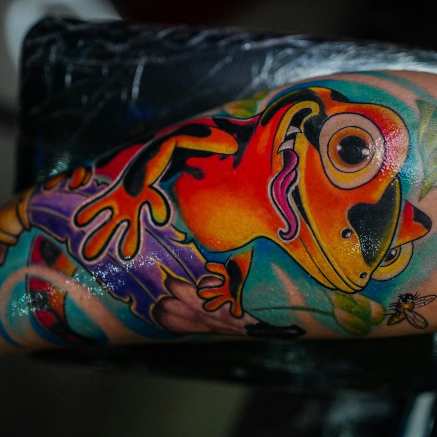 Farbe: bunter Frosch in Orange, Blau und Lila am Oberarm, frisch gestochen