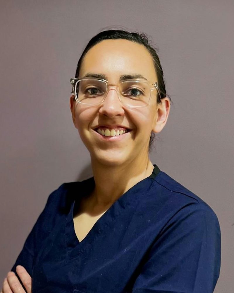 Portrait von Dr. Eva Waldeck, Tierärztin, mit Brille, zurückgebundenen Haaren und dunkelblauer Praxiskleidung